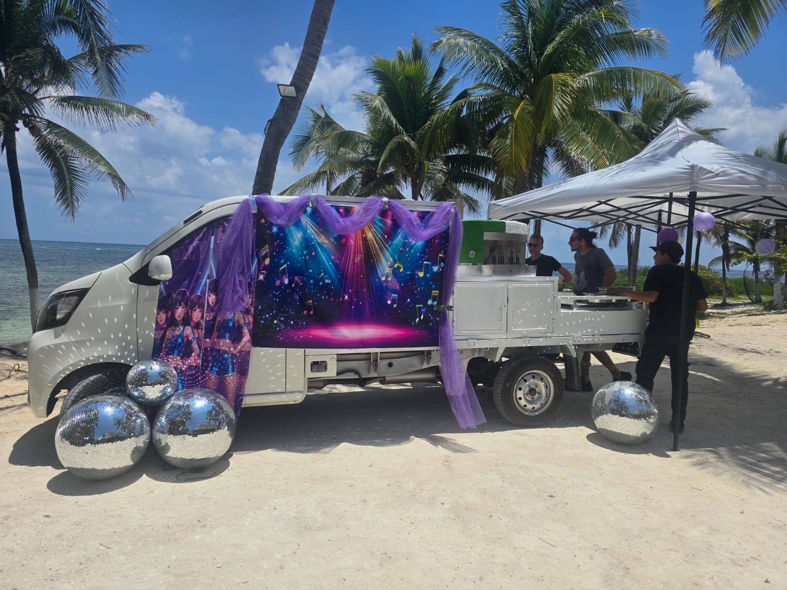 Dama Pizza Experience mobile pizza truck with themed decoration at a beachfront event.
