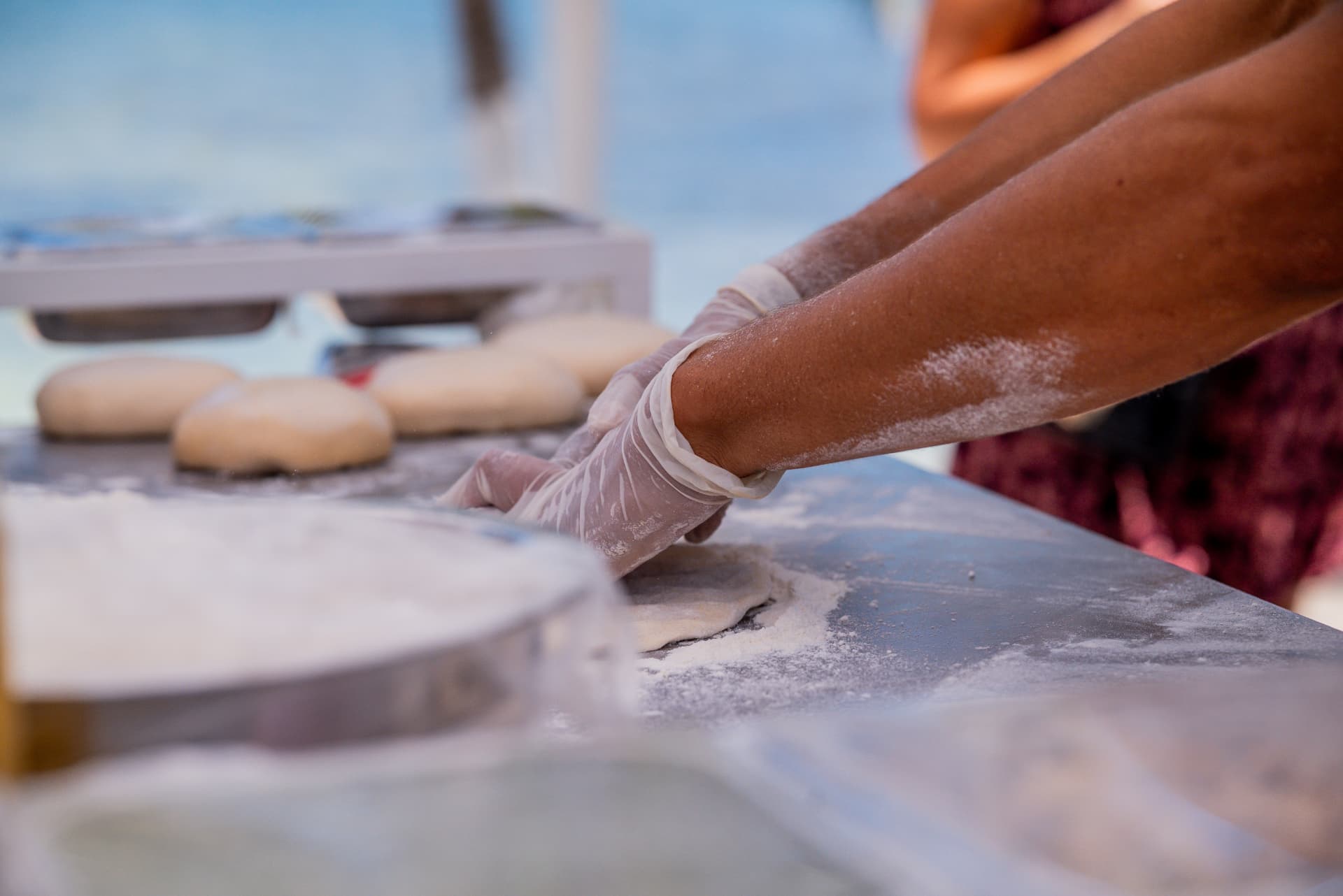 Dama Pizza Experience shaping pizza dough by hand at a beach event in the Riviera Maya