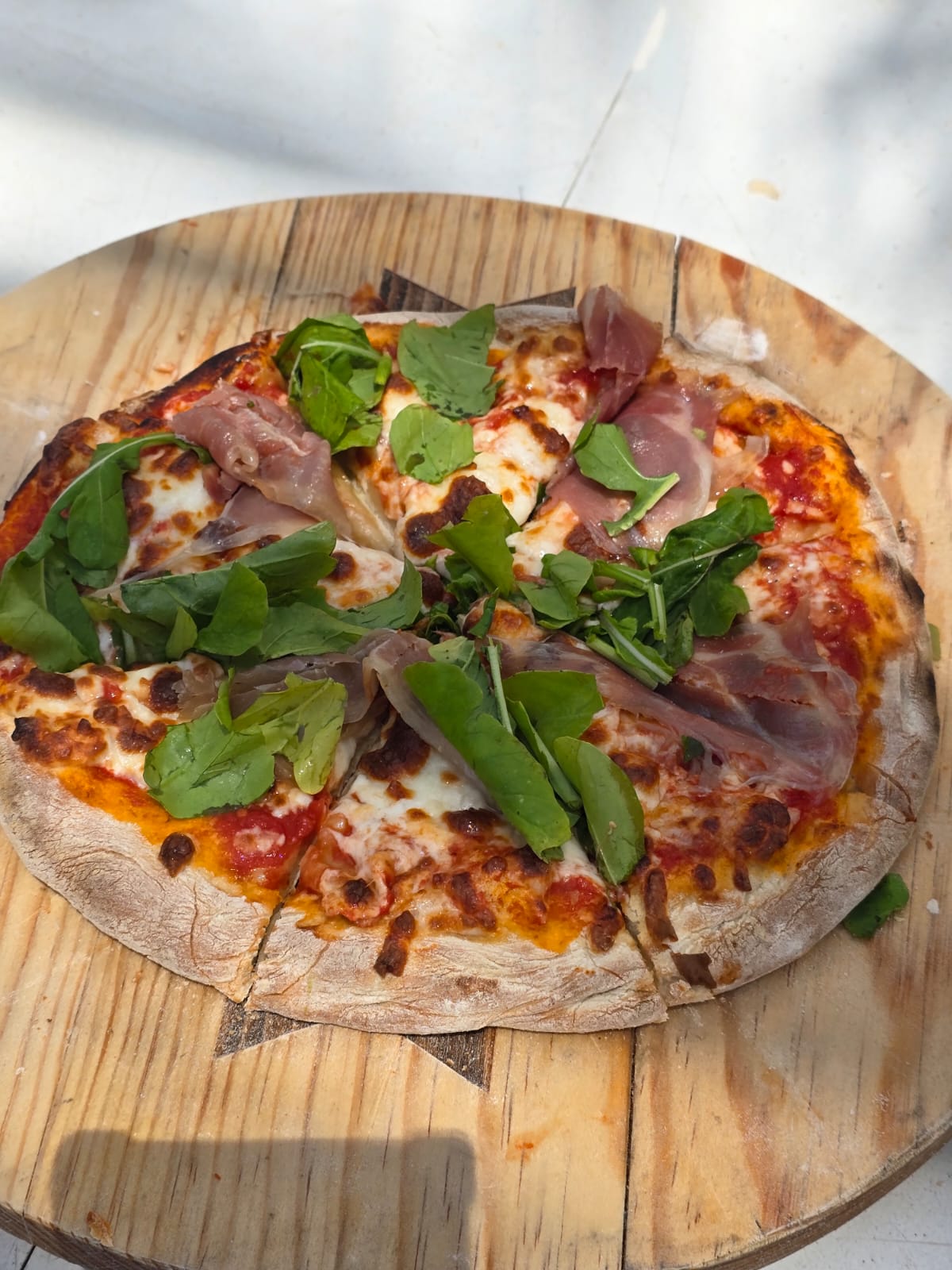 Napoletana pizza with prosciutto and arugula on a wooden board